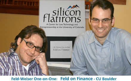 Two men posing for a photo in front of a sign for Silicon Flatirons, which is a center for law, technology, and entrepreneurship at the University of Colorado. The photo emphasizes the &lsquo;Feld on Finance&rsquo; event.